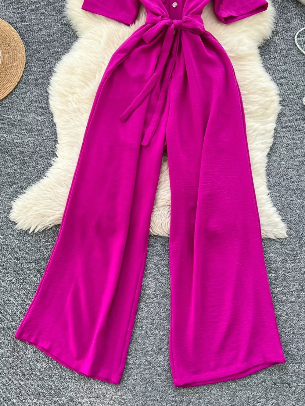 Belted wide-leg jumpsuit in pink with button detail and tie waist.