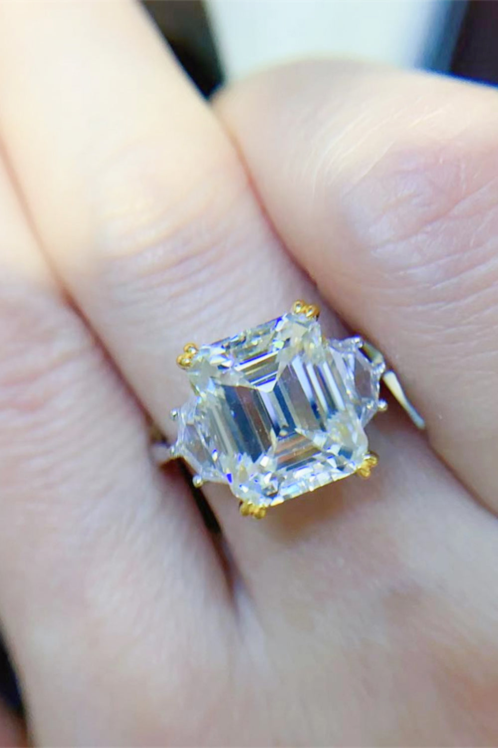 Emerald cut trilogy ring in silver with gold accents and clear stones.