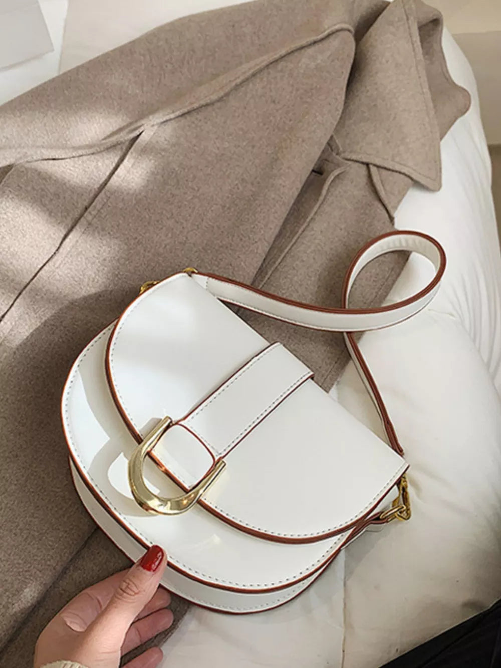 Chic white semi-circular flap crossbody bag with gold buckle detail.