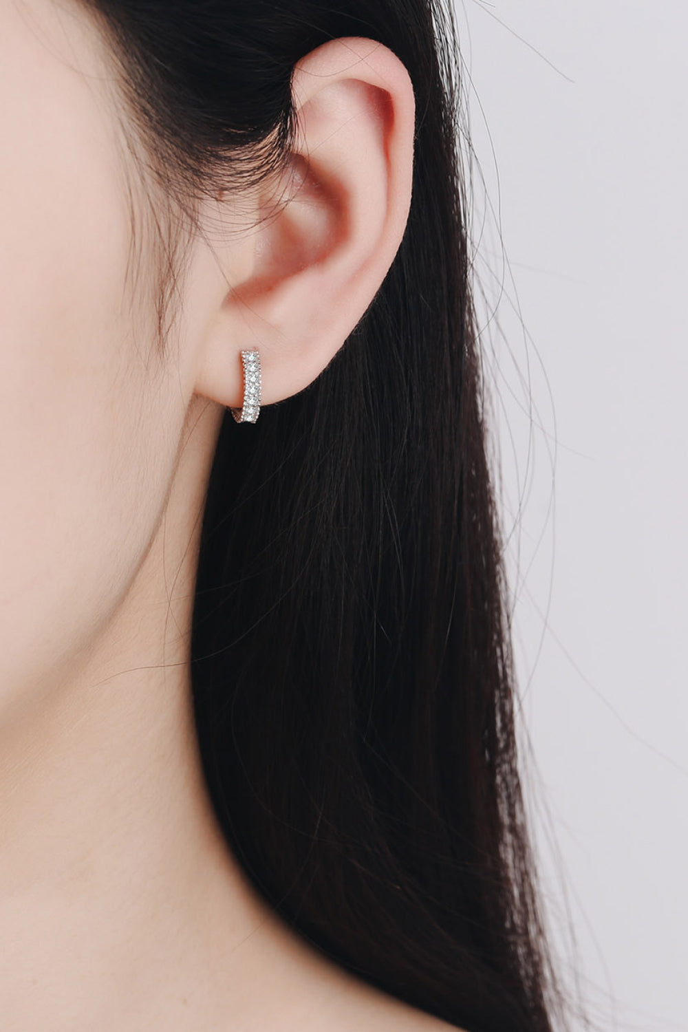 Silver hoop earrings with pavé and beaded details, worn by a woman.