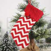 Red and white chevron cable knit Christmas stocking with pom poms on tree