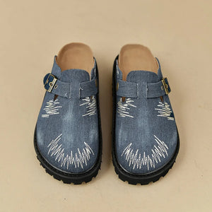 Embroidered denim platform clogs with buckle strap detail.
