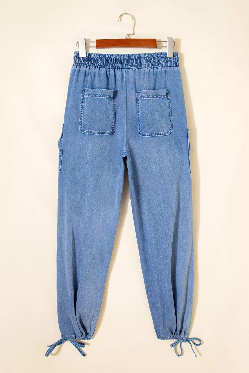 Light wash denim maternity cargo jeans with drawstring waist and cinched ankles.