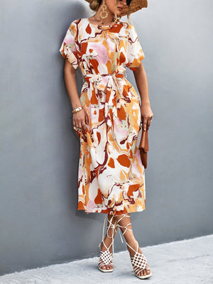 Women's abstract print midi dress in orange-red with tie waist and short sleeves.