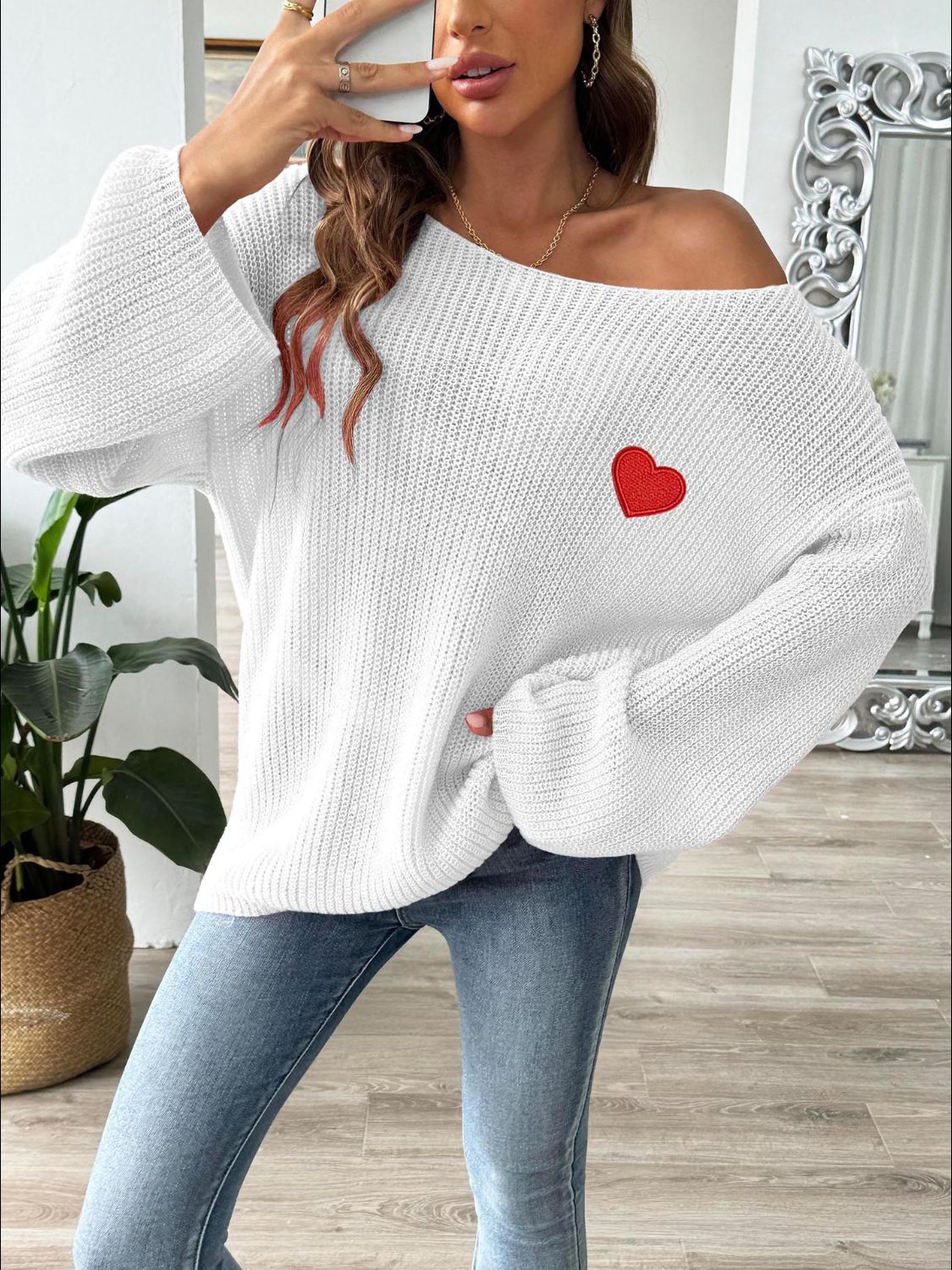 White slouchy boatneck knit sweater with embroidered red heart detail.