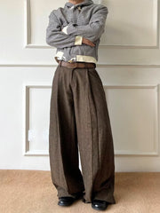 Men's brown wide-leg pleated trousers with a textured fabric and a brown belt.