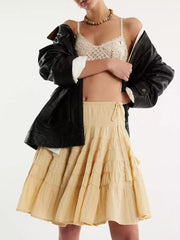 Tiered drawstring mini skirt in pastel yellow with a ruffled hem and tassel detail.