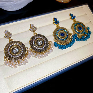 Beaded medallion and pearl drop earrings in white and cerulean, featuring intricate gold-tone metalwork.