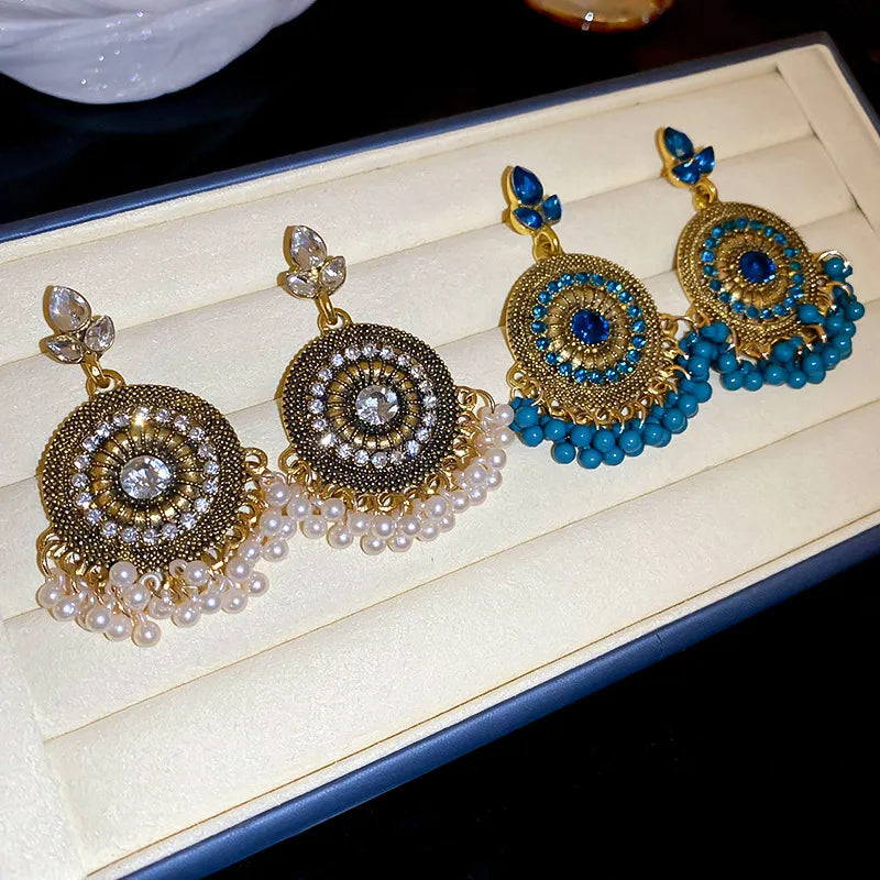 Beaded medallion and pearl drop earrings in white and cerulean, featuring intricate gold-tone metalwork.