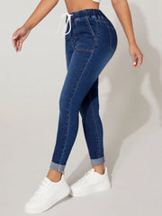 Medium wash denim joggers with drawcord waist and cuffed ankles.
