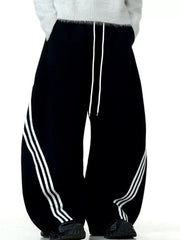 Men's black wide-leg sweatpants with white side stripes and drawstring waist.