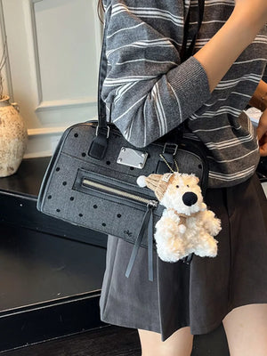 Black polka dot shoulder bag with a zippered front pocket and a plush teddy bear charm.