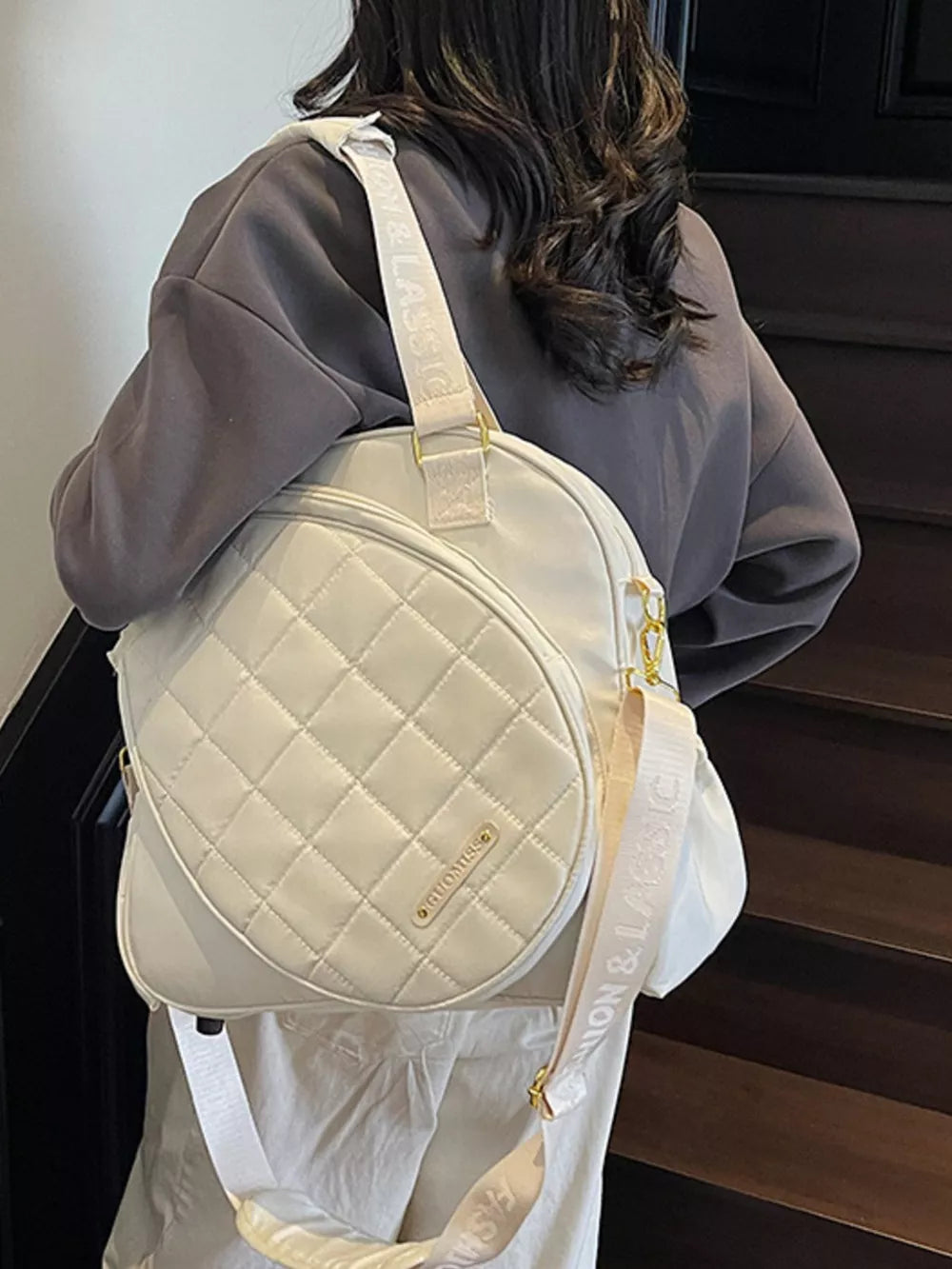 Quilted off-white Oxford bag with adjustable strap for racket storage.
