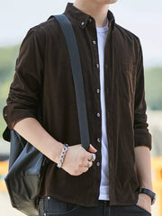 Men's chocolate corduroy button-down shirt with pocket, worn over a white tee.