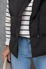 Black padded stand collar vest with zipper detail over a striped long sleeve shirt and jeans.