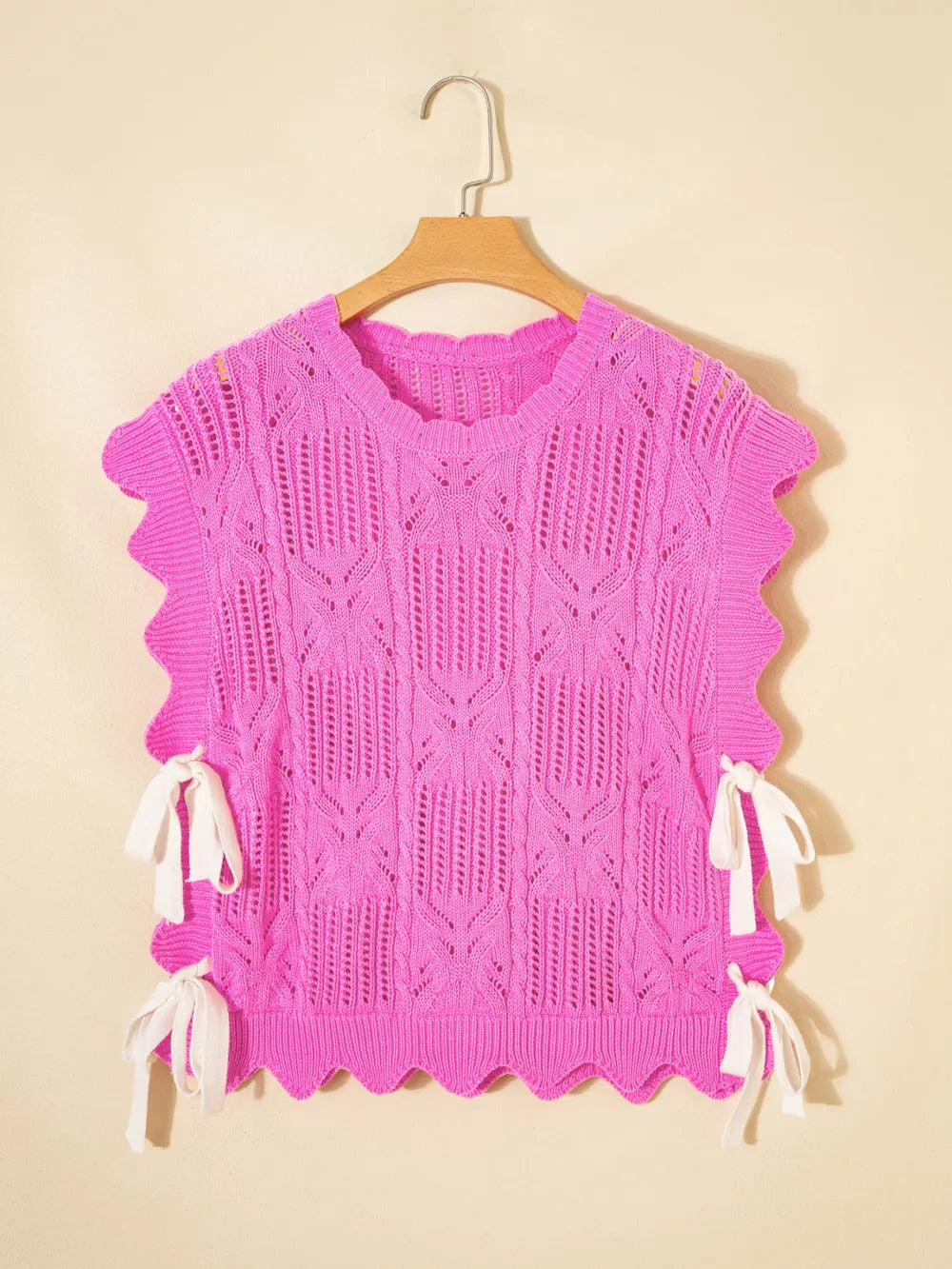 Pink openwork knit sweater vest with cable knit pattern and tie details.