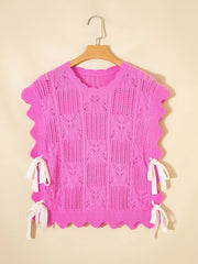 Pink openwork knit sweater vest with cable knit pattern and tie details.