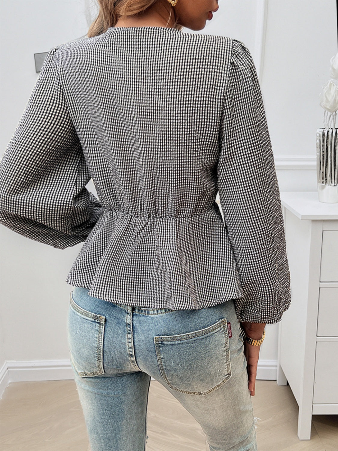 Black gingham peplum blouse with cinched waist and puff sleeves, styled with jeans.