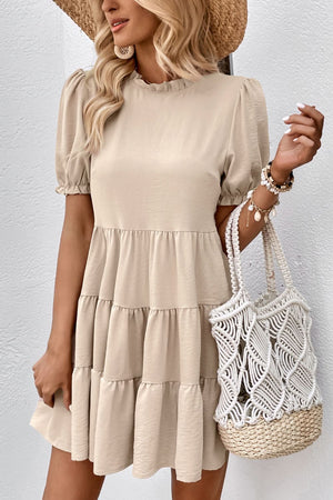 Beige tiered mini dress with ruffled neckline and puff sleeves.