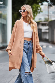 Tan open-knit longline cardigan with side slits and pockets, acrylic material.