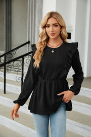 Black textured ruffle peplum blouse with long sleeves and a round neckline.