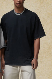 Washed black oversized t-shirt with raw hem and crewneck, styled with a chain necklace.