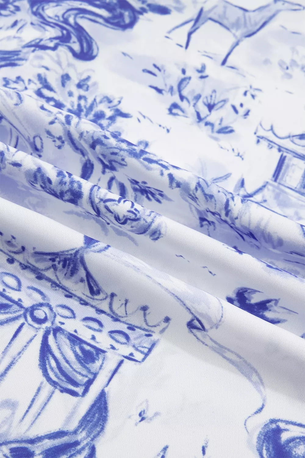 Blue toile print blouse with V-neck and striped accents, showing fabric detail.