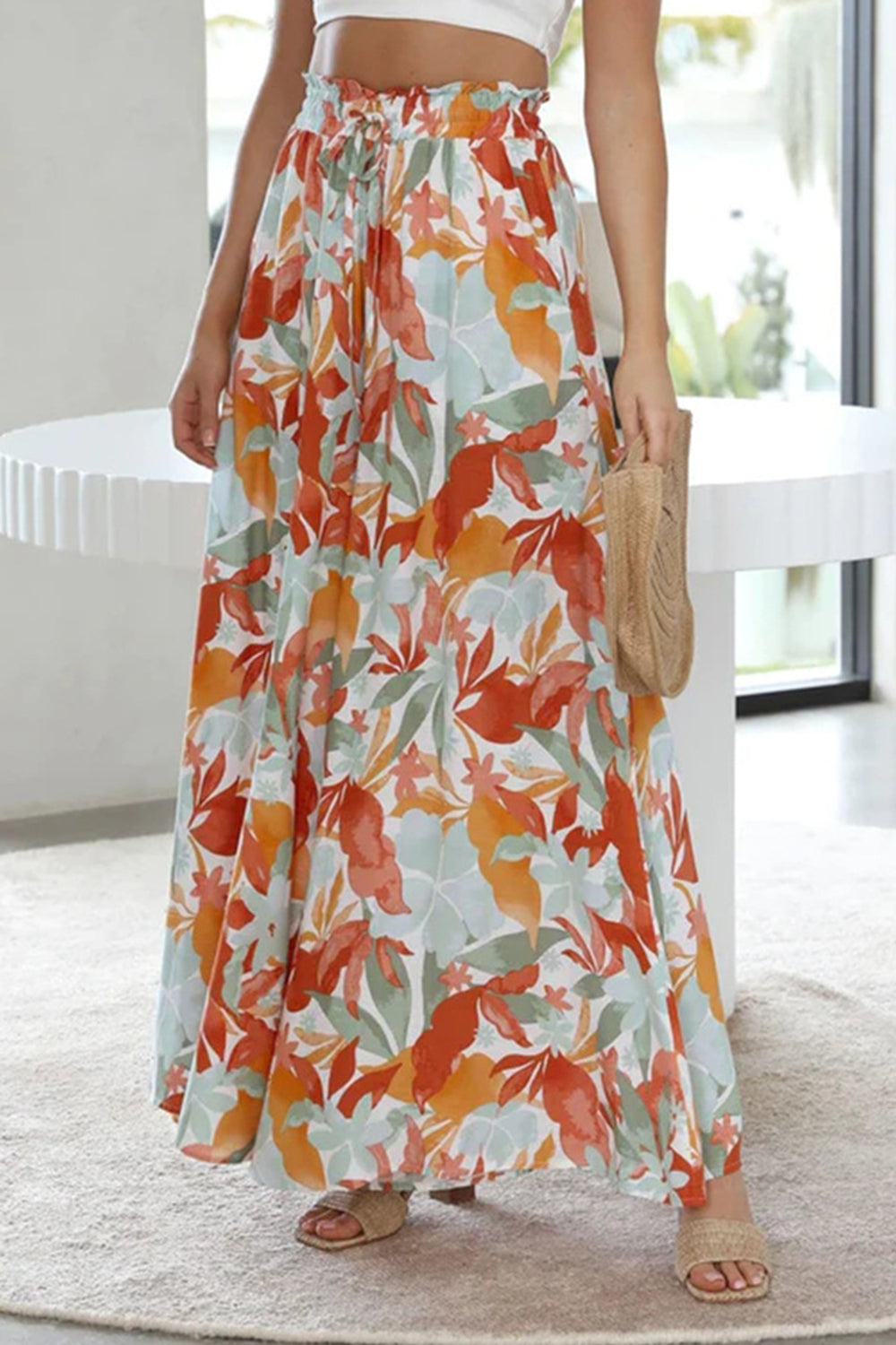 Botanical print palazzo trousers with a drawstring waist and wide legs in orange-red, aqua, and green.