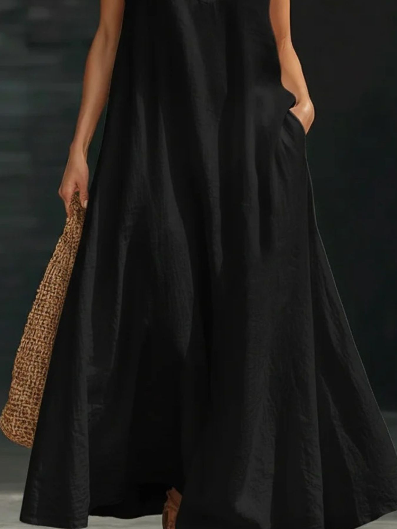 Black halter neck maxi dress in cotton linen with pockets, styled with a straw bag.