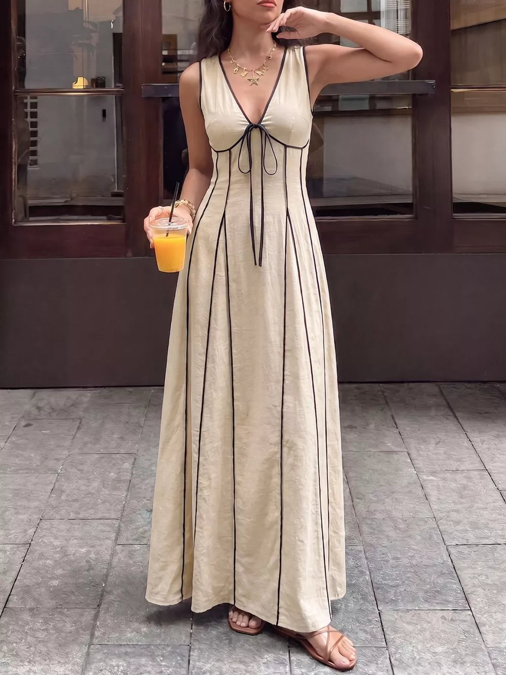 Elegant tied maxi dress in cream with black piping details and a deep V-neck.