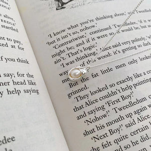 Sterling silver pendant necklace with a single pearl, delicate chain, elegant design.