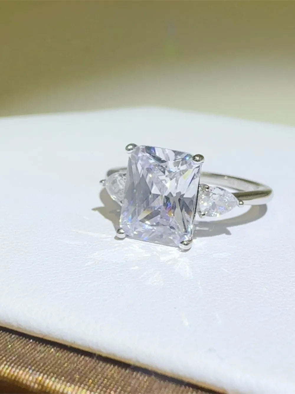 Silver ring with emerald cut center stone and pear accent stones