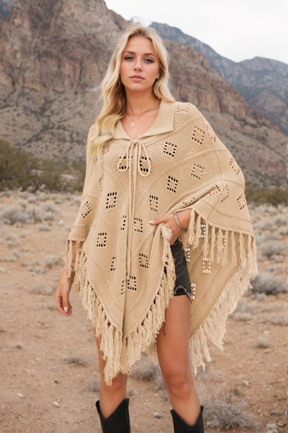 Tan geometric knit poncho with fringe and tie neck, acrylic material.
