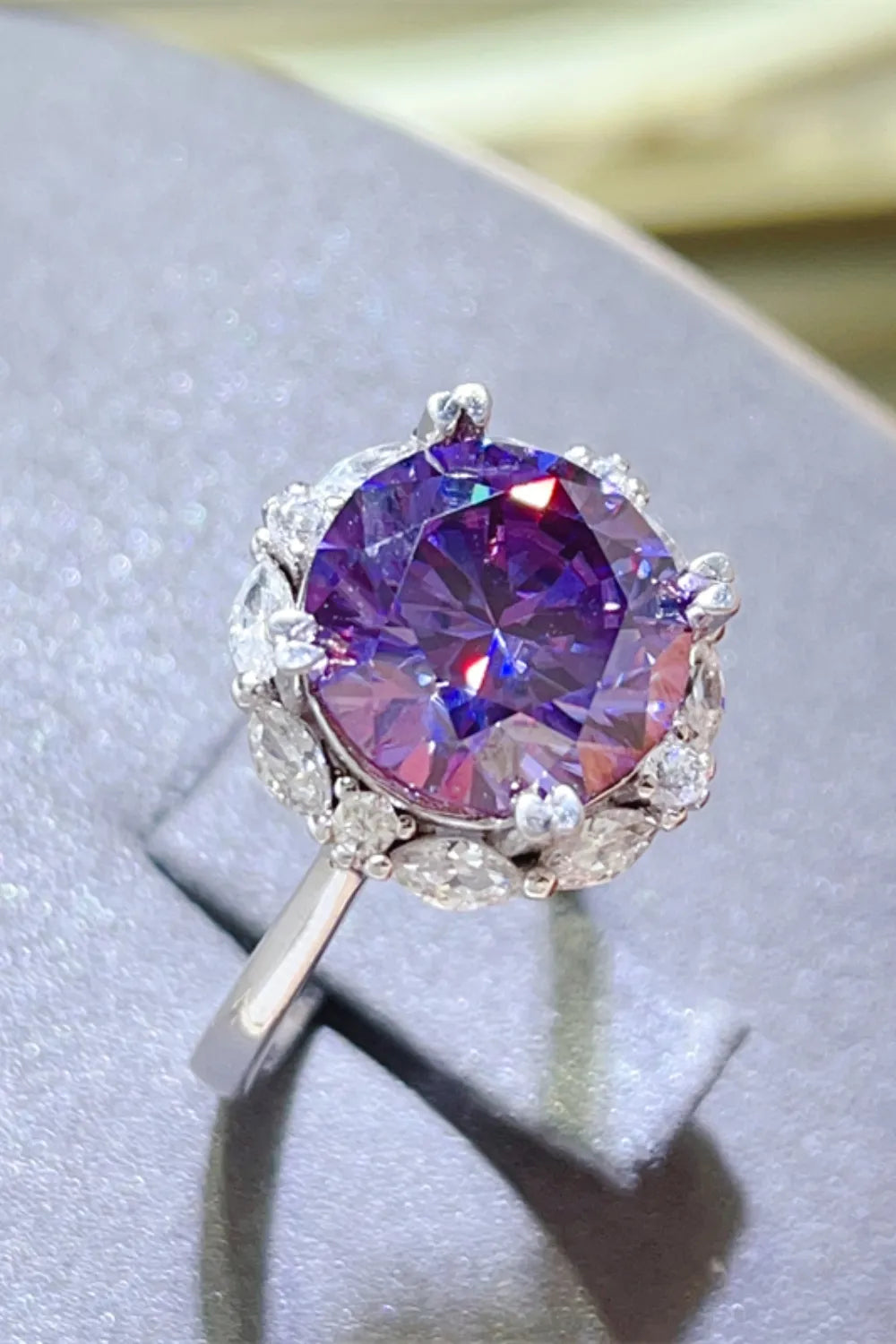 Amethyst halo cocktail ring in silver with a large round purple amethyst and surrounding white stones.