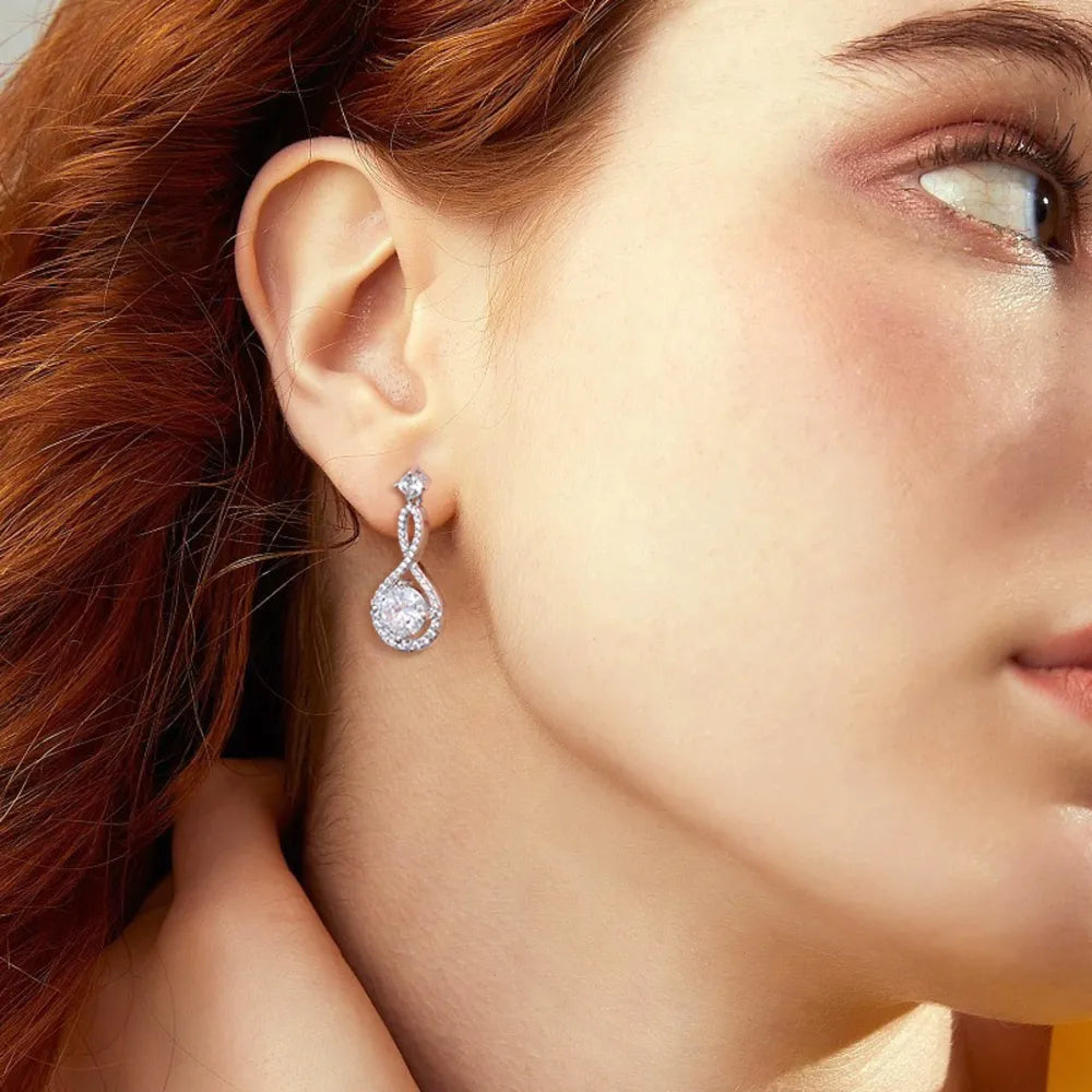 Infinity drop earrings with aquamarine and white stones.