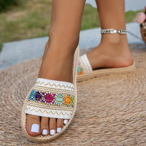 Embossed strap open-toe flat sandals with colorful embroidered detail and braided trim.