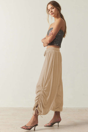 Tan gathered ankle-tie balloon trousers with a drawstring waist and ruched detail.