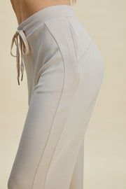 Beige joggers with drawstring waist and subtle pocket detail.