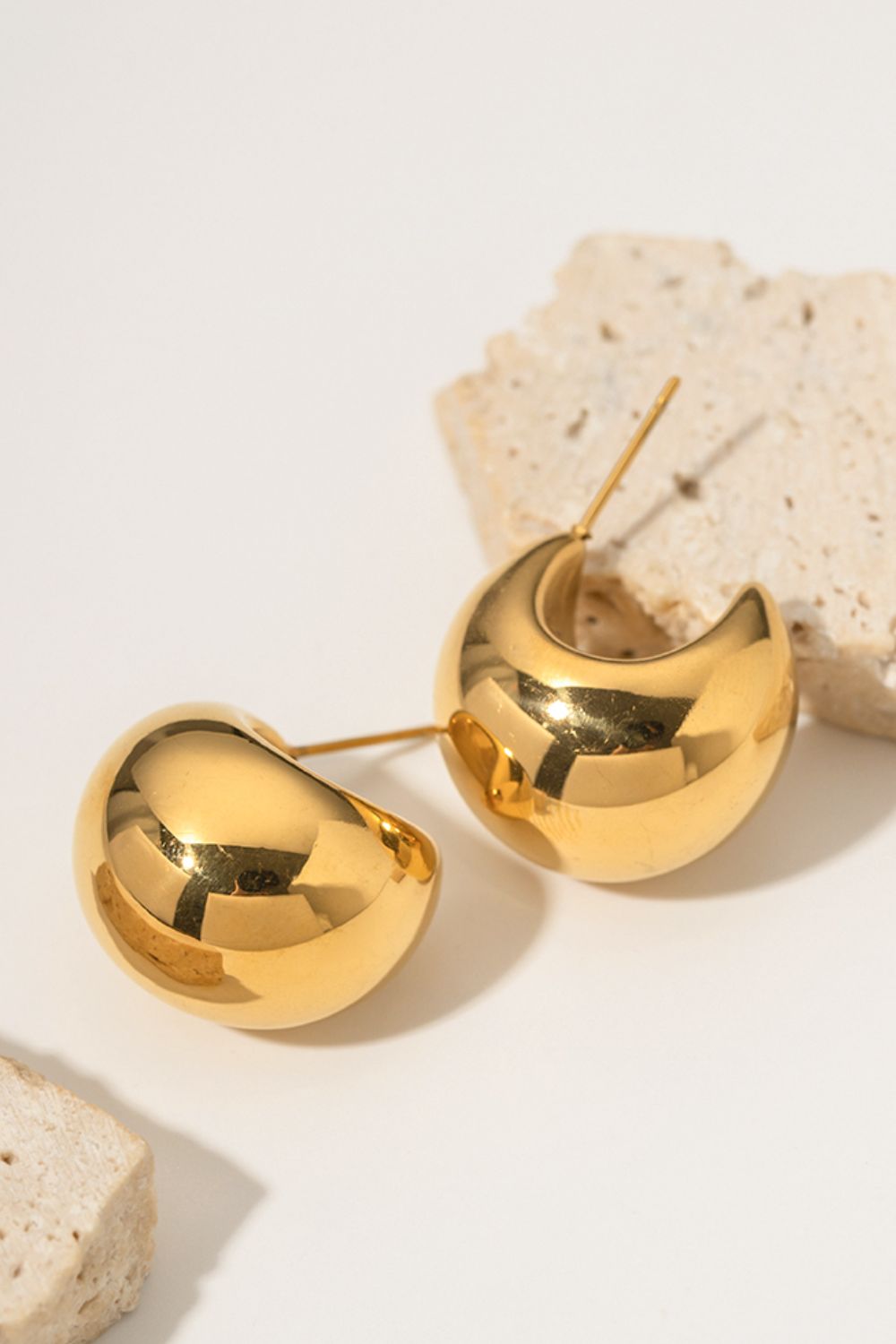 Gold sculptural crescent hoop earrings with a polished finish.
