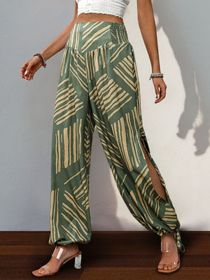 Moss green palazzo trousers with abstract print, smocked waist, and high slit legs.