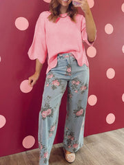 Pink knit top with scalloped sleeves and hem, paired with light wash floral print wide leg jeans.