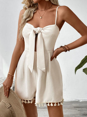Beige textured romper with bow front, cut-out detail, and tassel hem.