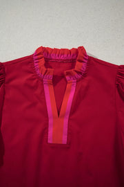 Red maternity blouse with ruffled neckline and striped V-neck detail.