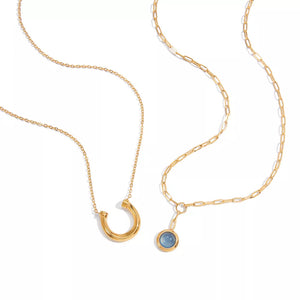Gold-plated layered necklaces, one with a horseshoe pendant, the other with a blue stone pendant.