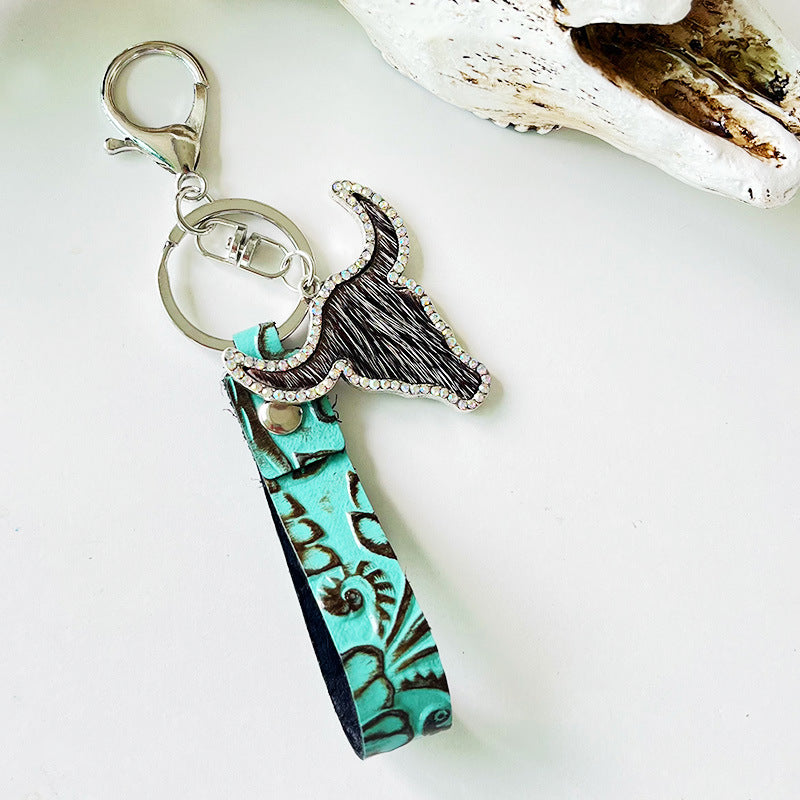 Turquoise embossed leather keychain with a crystal-trimmed bull head charm and fur detail.