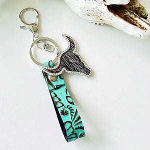 Turquoise embossed leather keychain with a crystal-trimmed bull head charm and fur detail.