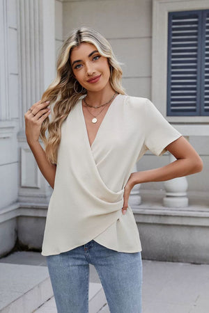 Cream draped front short sleeve blouse with a V-neck and textured fabric.