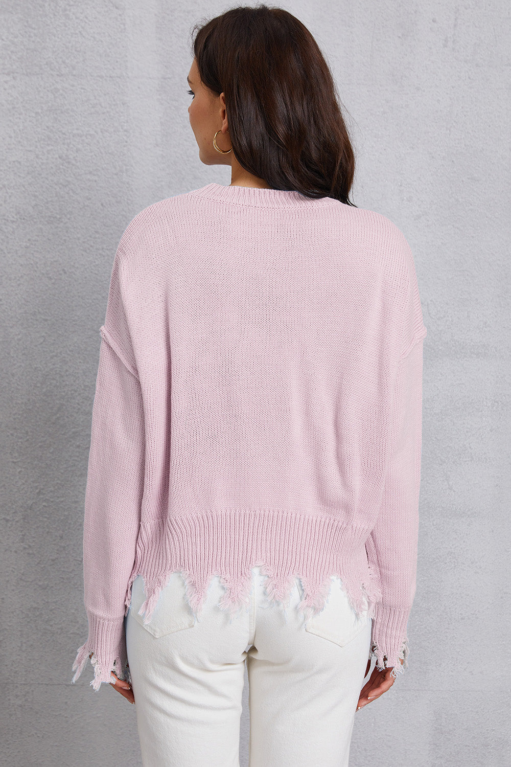 Blush pink acrylic knit sweater with distressed hem and frayed edges.