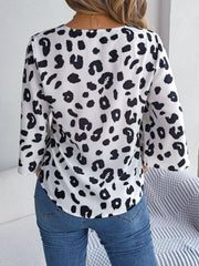 White leopard print tie-front blouse with black spots, long sleeves, and a V-neck.