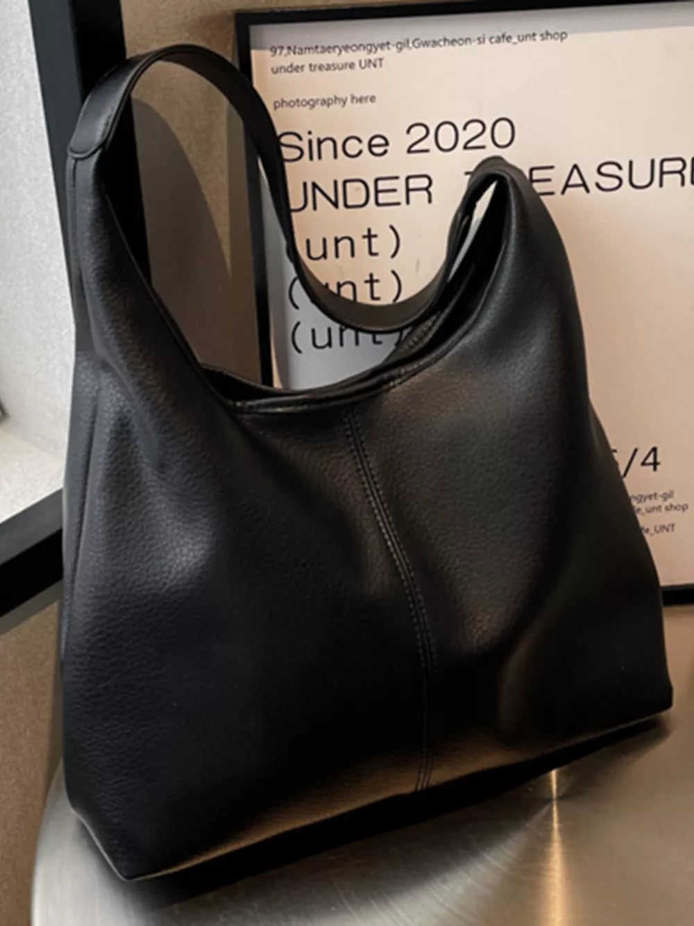 Black pebbled leather hobo shoulder bag with a slouchy silhouette and single strap.